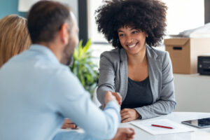 A young sales professional shaking hands with her clients